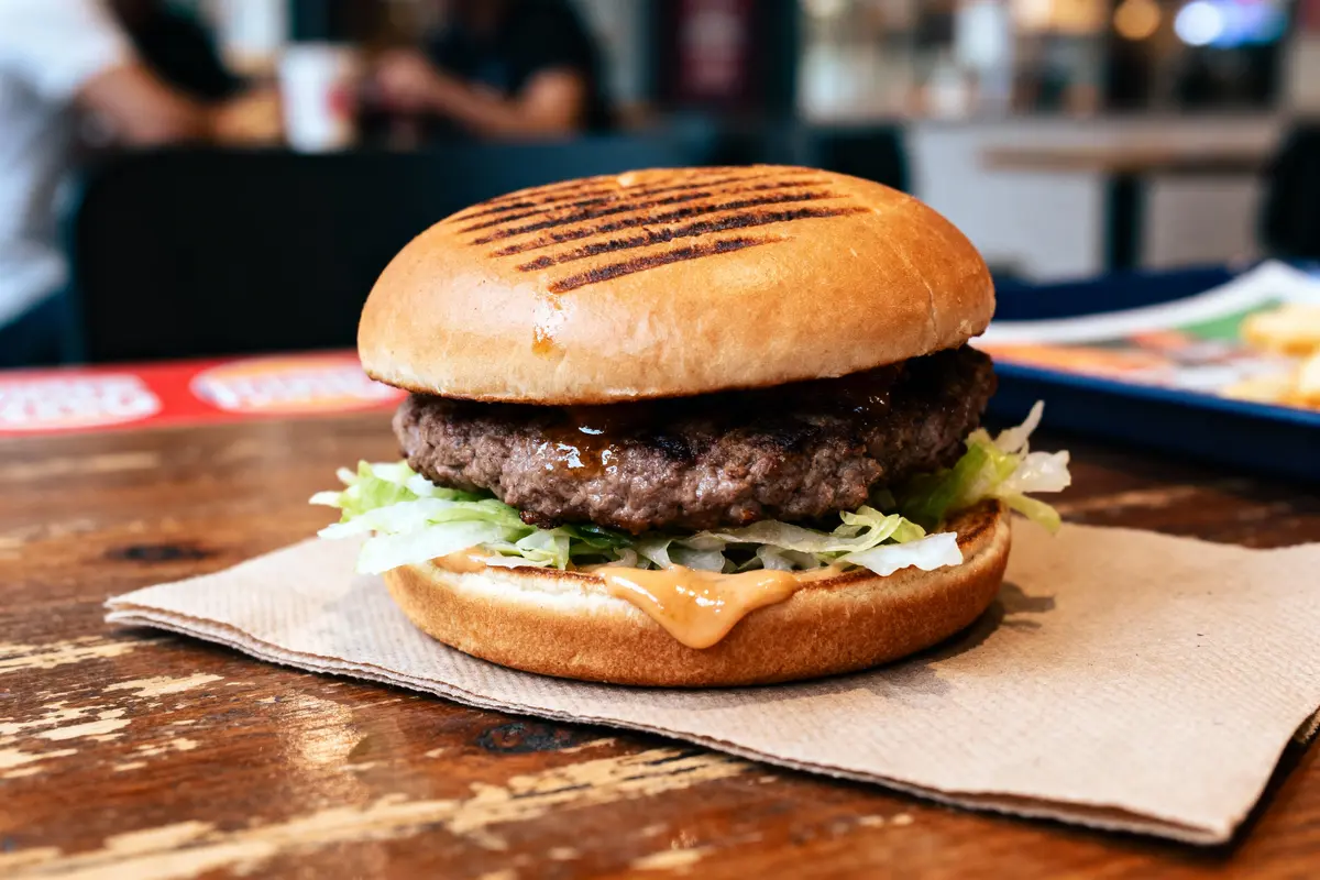 pexels-michal-pech-213601-757318 (1) Burger appétissant sur une table en bois, avec salade, viande, pain brioché et sauce.