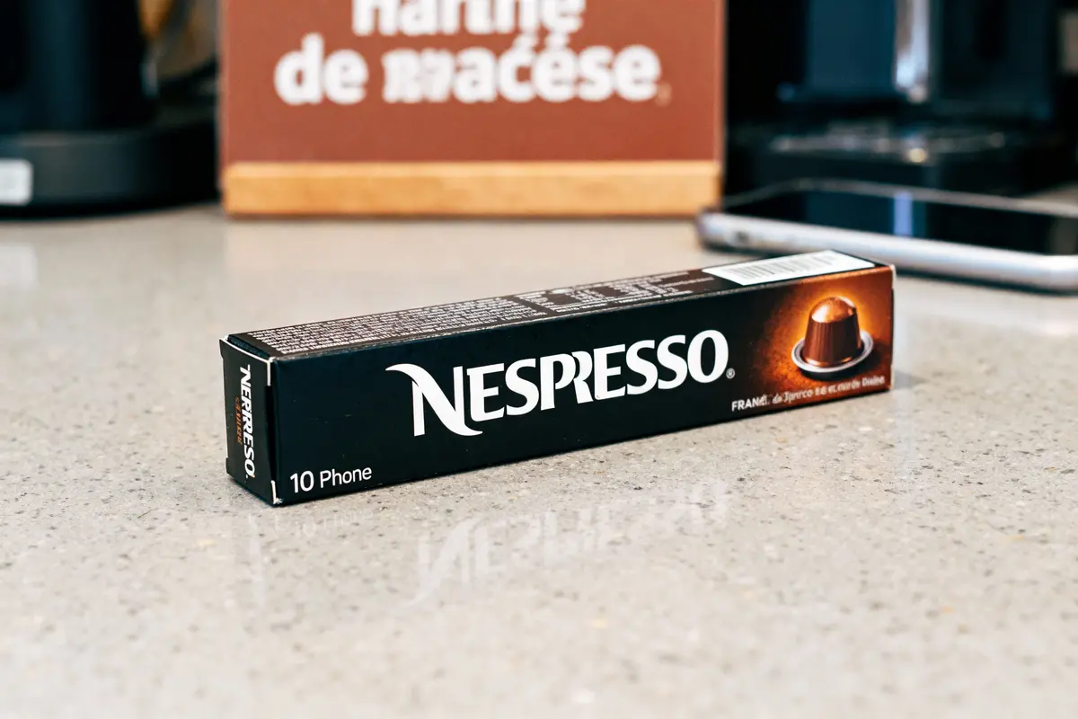 pexels-michal-pech-213601-757318 (1) Boîte noire de capsules Nespresso sur un comptoir, avec téléphone flou et arrière-plan marron.