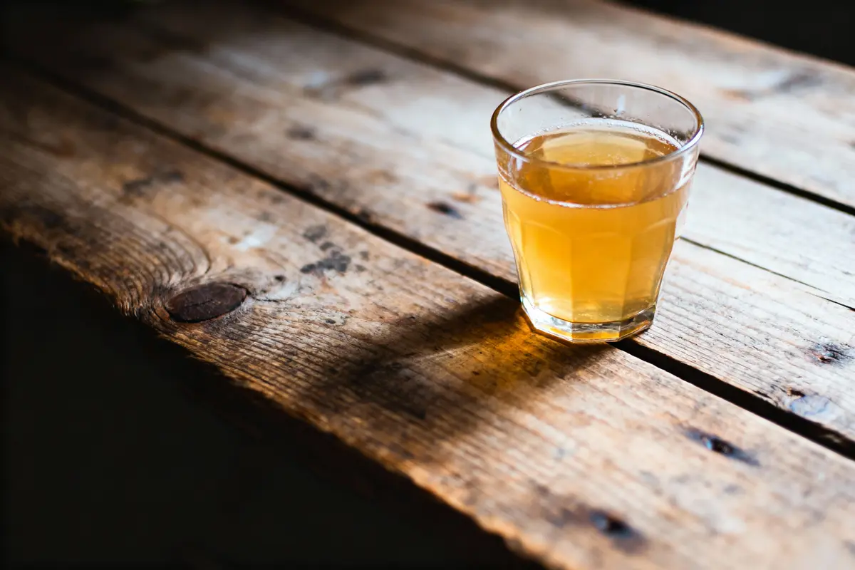 pexels-michal-pech-213601-757318 (1) Verre de boisson orange sur table en bois rustique avec éclairage naturel.