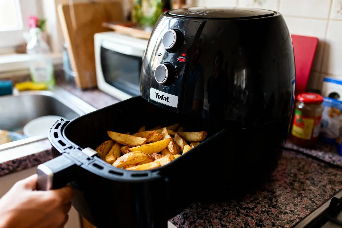 pexels-michal-pech-213601-757318 (1) Frites dans une friteuse à air noir Tefal, sur un plan de travail de cuisine.
