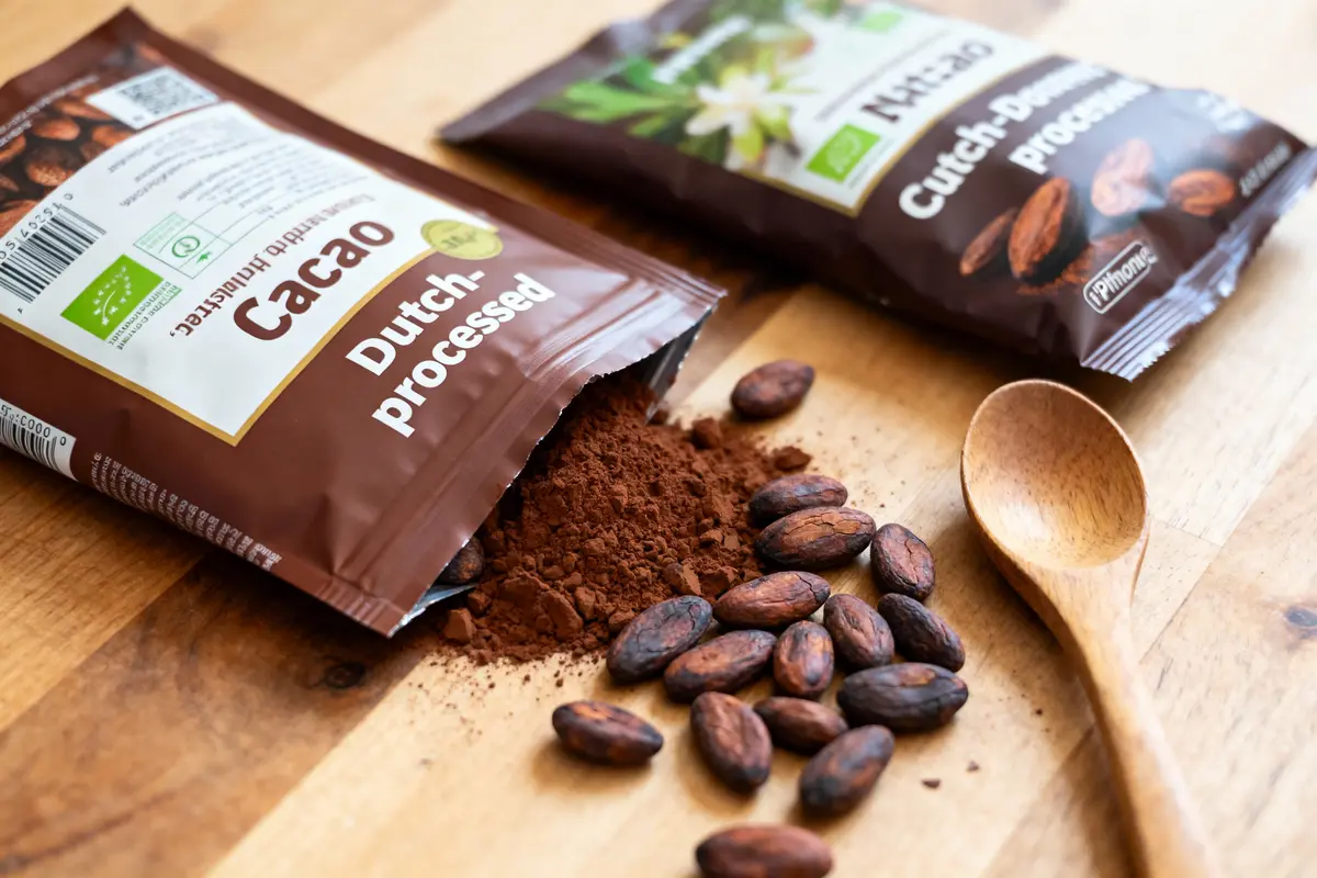 pexels-michal-pech-213601-757318 (1) Deux sachets de cacao traité, poudre de cacao renversée, fèves de cacao, cuillère en bois sur table.