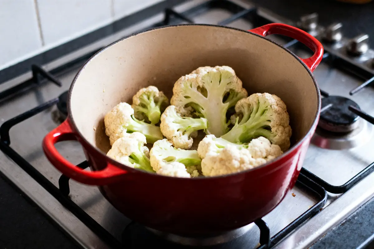 pexels-michal-pech-213601-757318 (1) Chou-fleur dans une marmite rouge sur une cuisinière à gaz, prêt pour la cuisson.