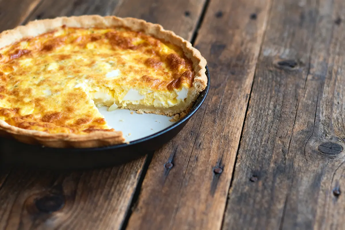 pexels-michal-pech-213601-757318 (1) Quiche lorraine de grand-mère sur table rustique avec une part manquante